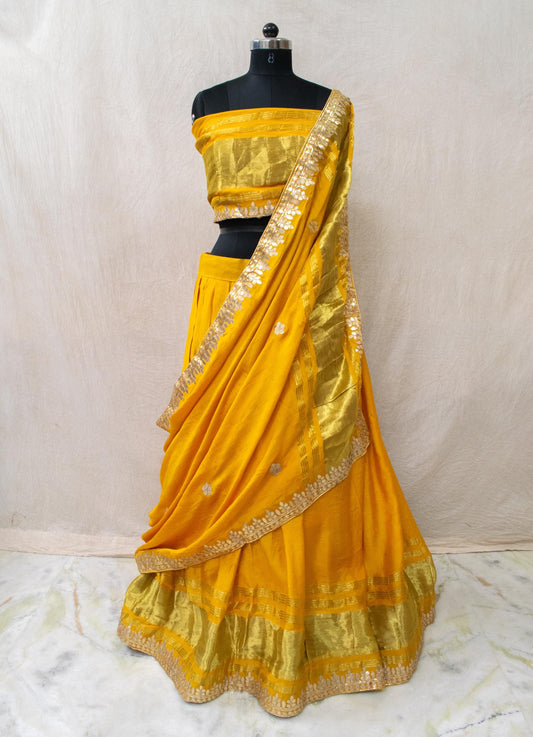Yellow silk lehenga choli with gota patti work, perfect for festive occasions and traditional celebrations.