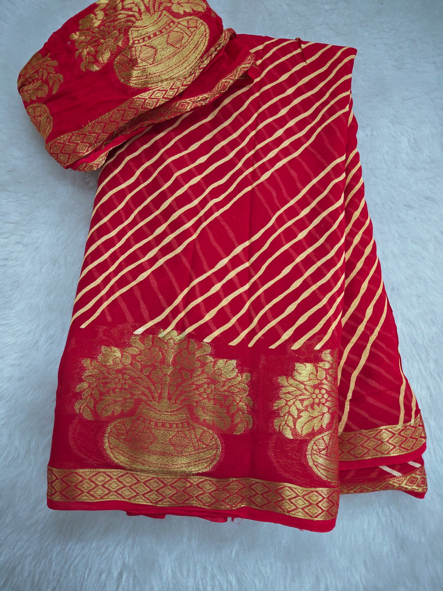 Red pure georgette leheriya saree laid flat, showcasing the fabric and gold border.